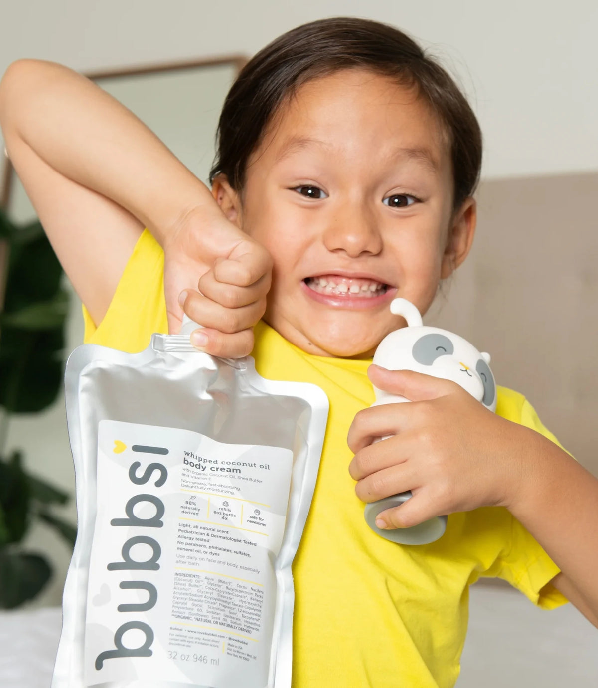 Child holding up a 32 oz Bubbsi body cream refill size and Bubbsi body cream bottle