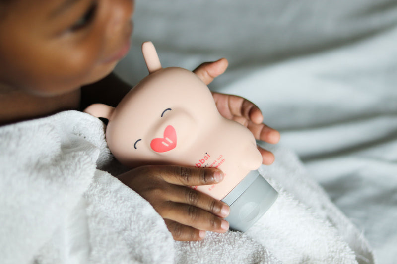 Child holding a Bubbsi bottle on a soft surface