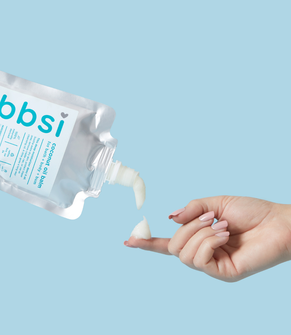Hand applying a white cream from a bbsi container against a light blue background